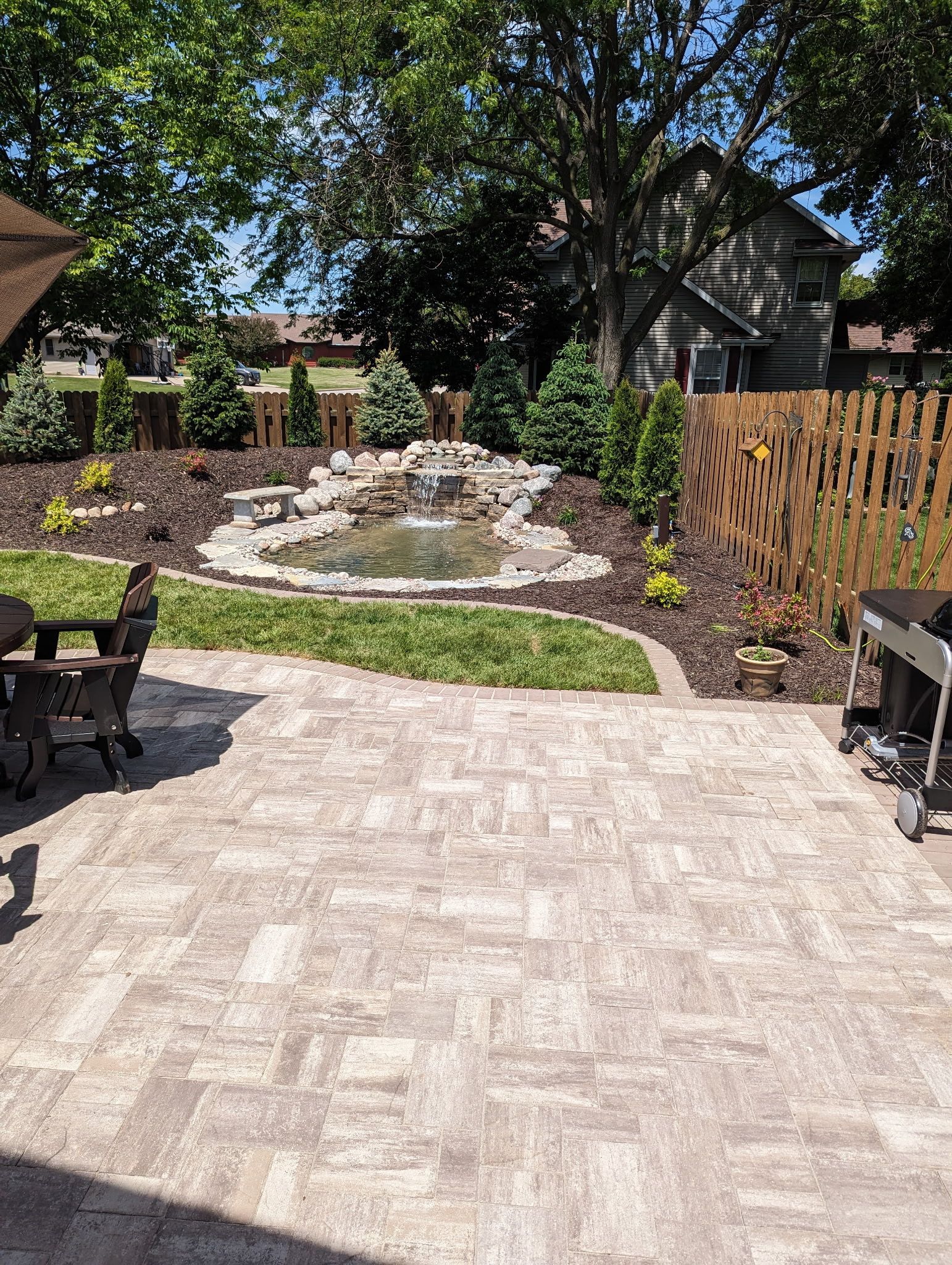 A patio with a table and chairs and a waterfall in the backyard.