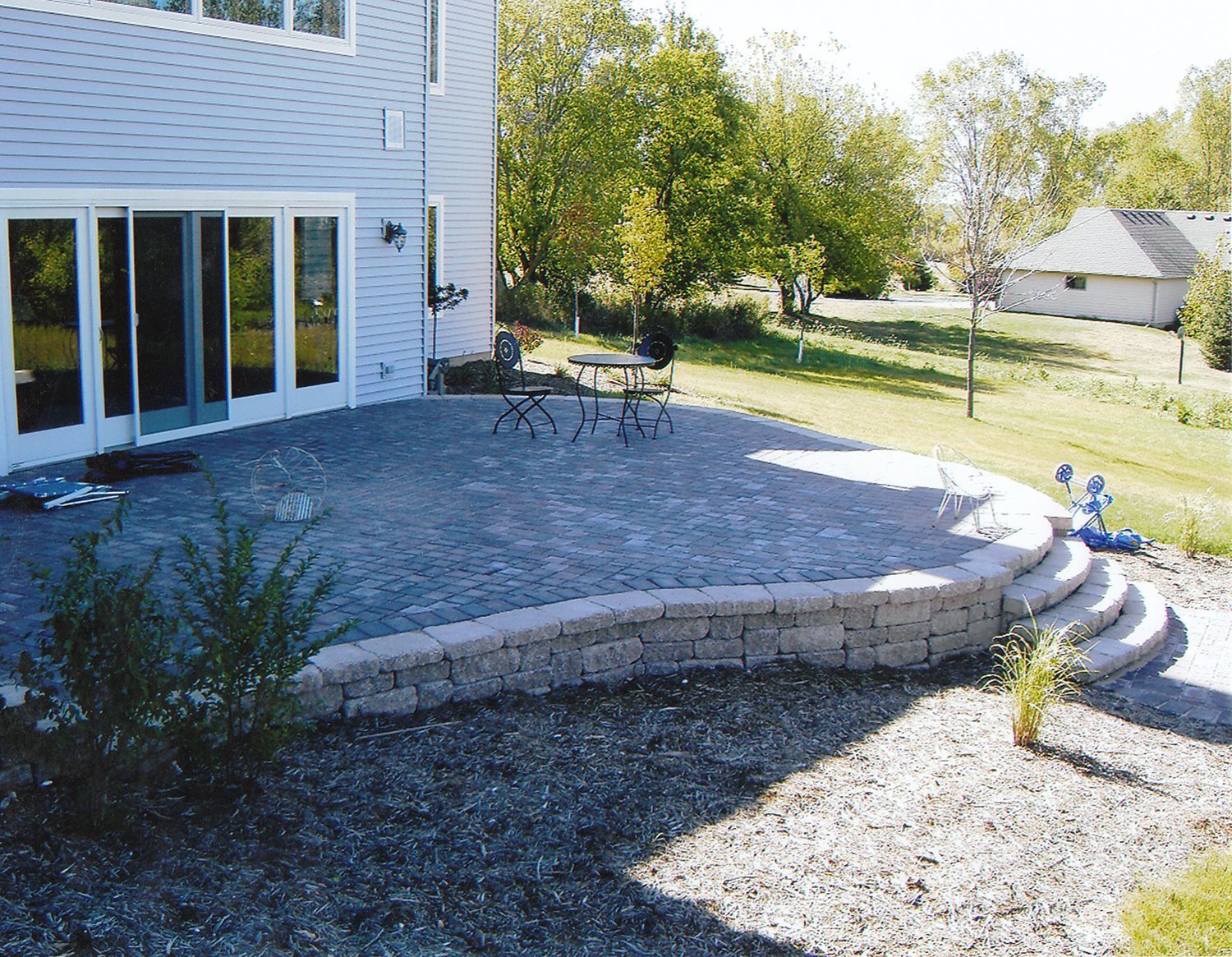 A patio with a table and chairs in front of a house