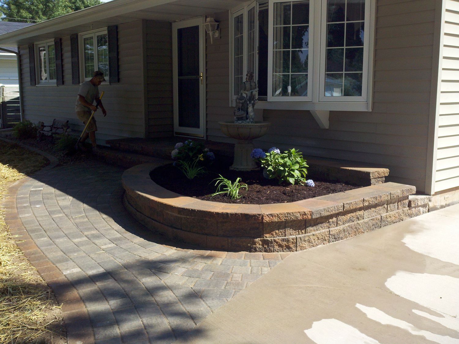 A man is sweeping the sidewalk in front of a house