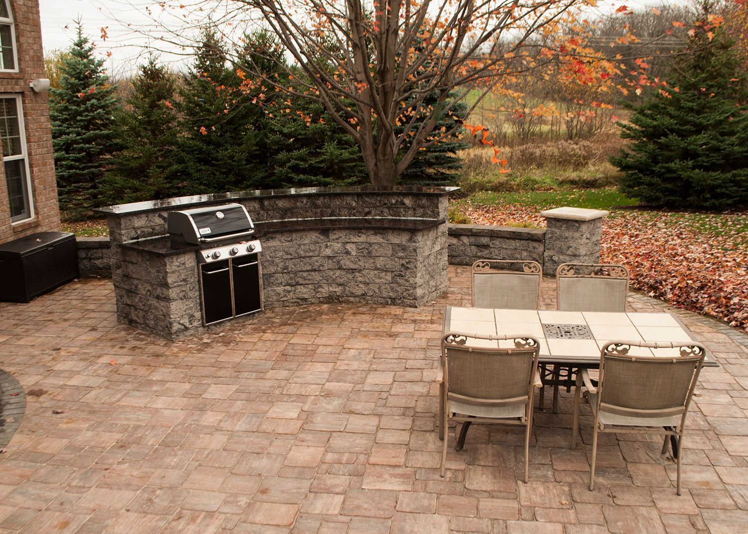 A patio with a table and chairs and a grill.