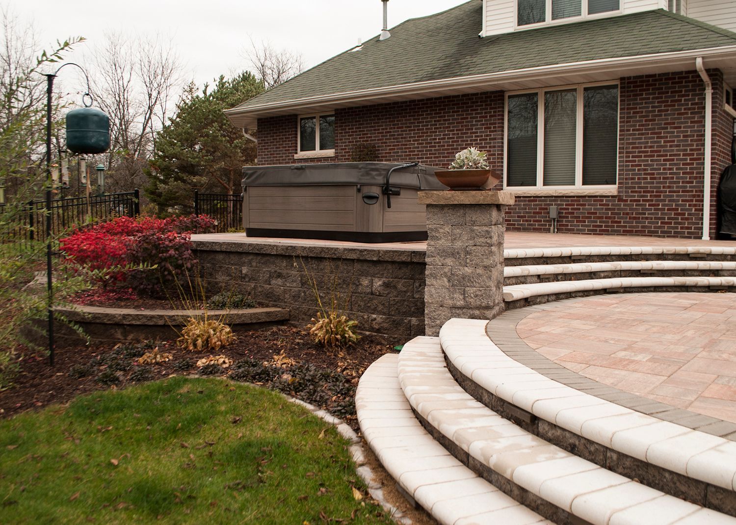 A brick house with a hot tub on the back patio.