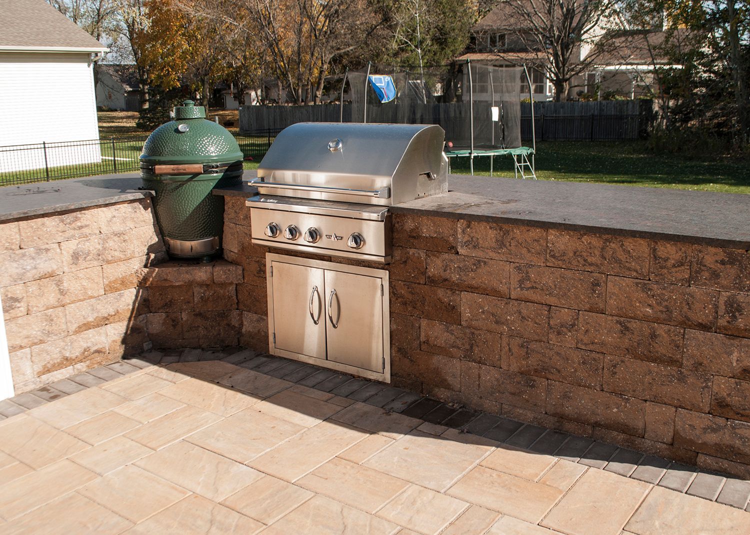 A grill is built into a brick wall on a patio.