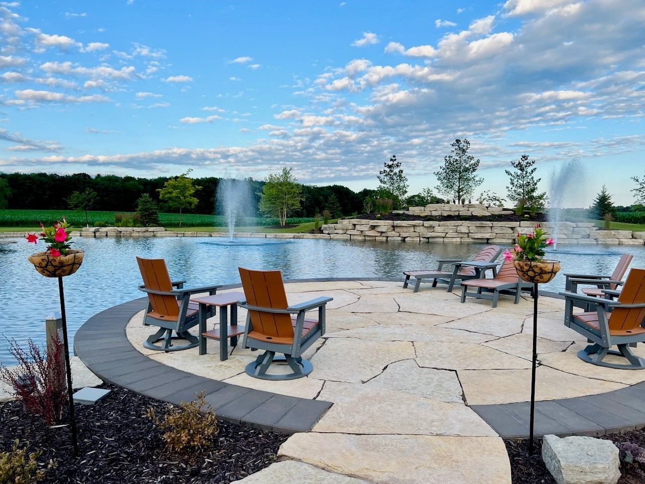 A patio with chairs , tables and a fountain in the background.