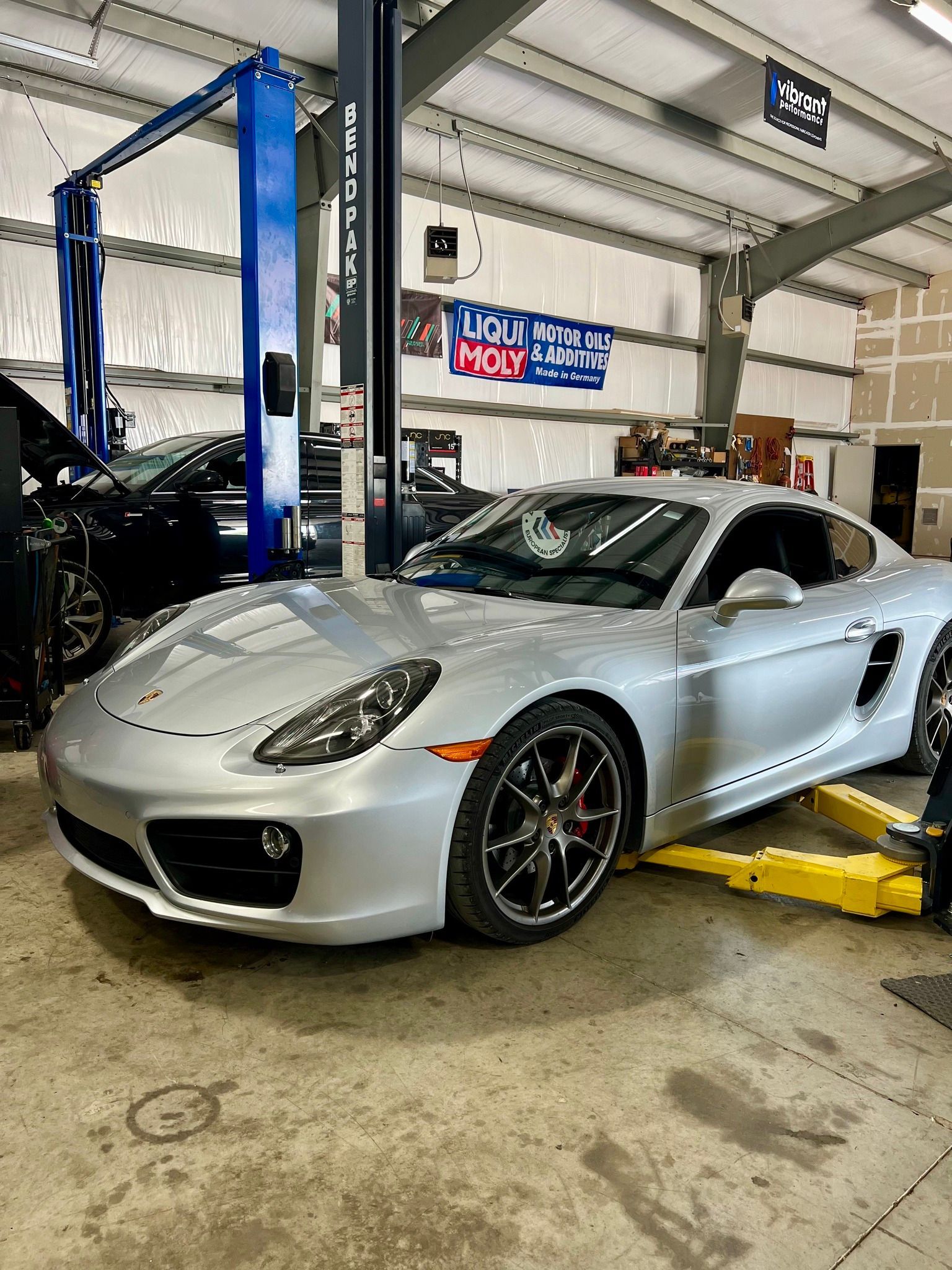 A silver sports car is parked on a lift in a garage.