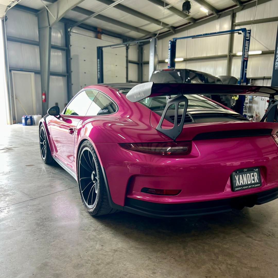 A pink sports car is parked in a garage.