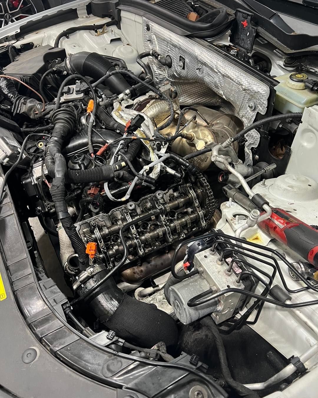 A close up of a car engine with a lot of wires coming out of it.