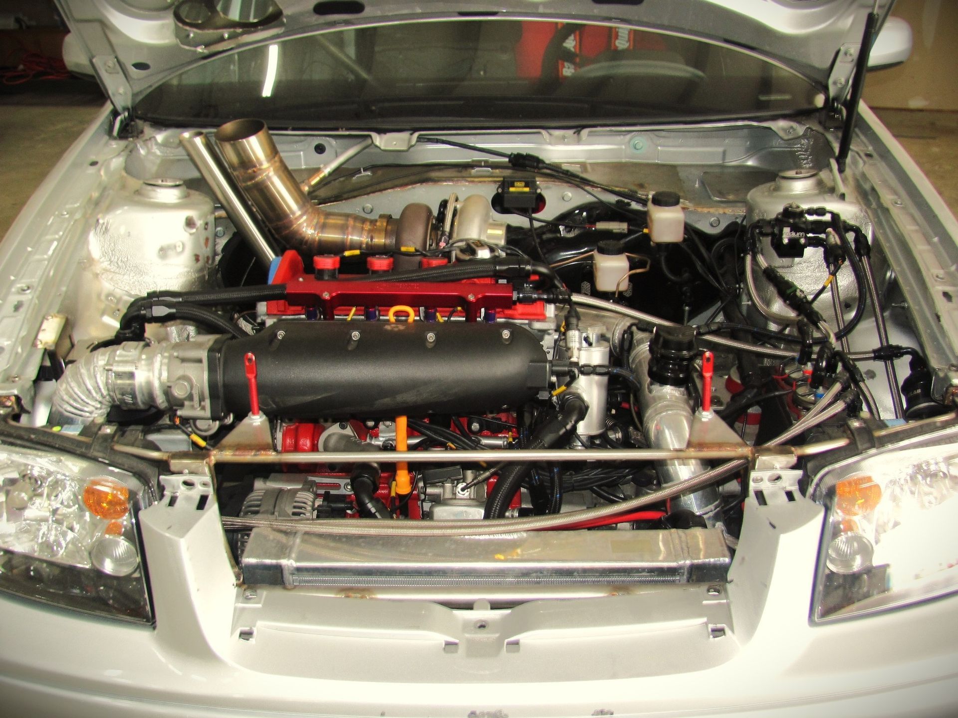 A white car with the hood open and the engine exposed