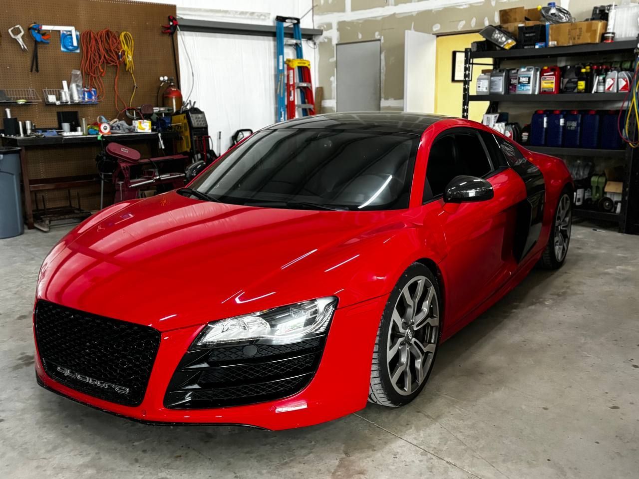 A red sports car is parked in a garage