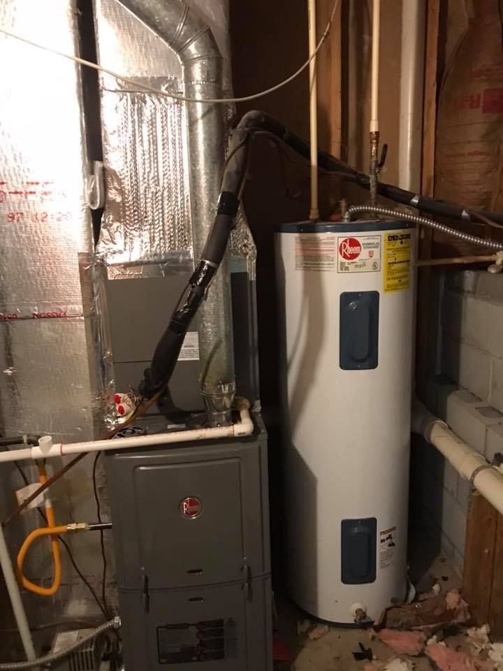 A water heater is sitting next to a furnace in a basement.
