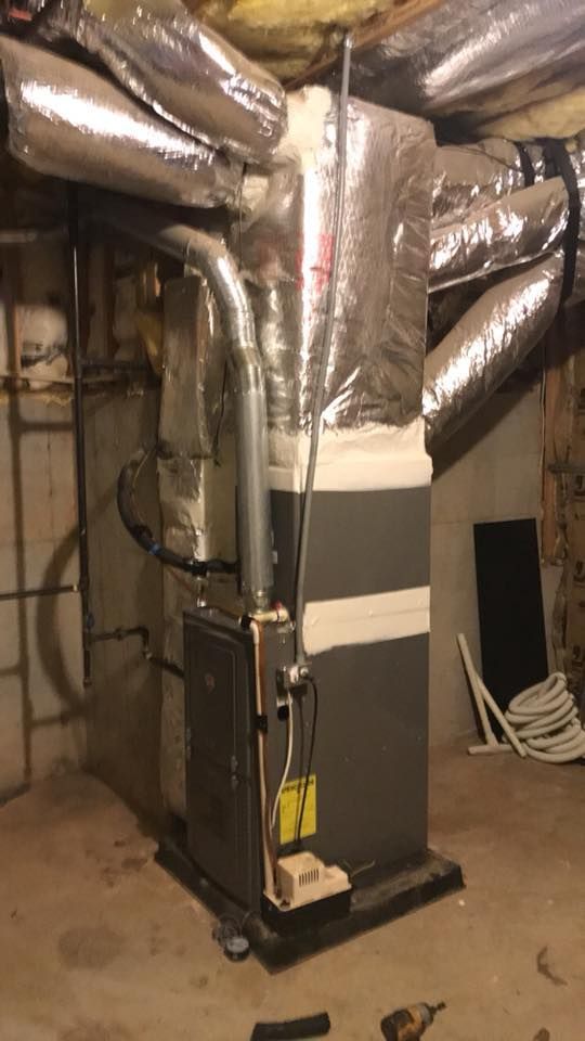 An air conditioner is sitting in a basement next to a ladder.