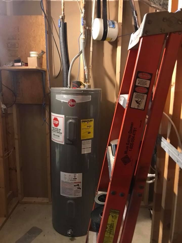 A red ladder is sitting next to a water heater in a room.