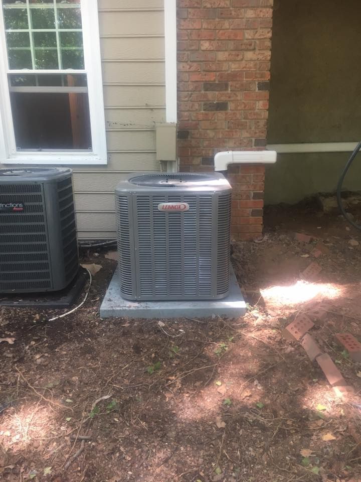 Two air conditioners are sitting on the side of a brick house.