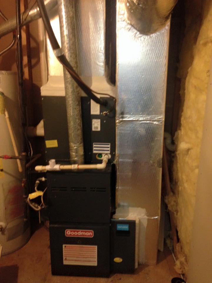 An air conditioner is sitting in a basement next to a wall.