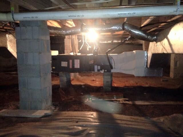 A basement under construction with a light shining through the pipes