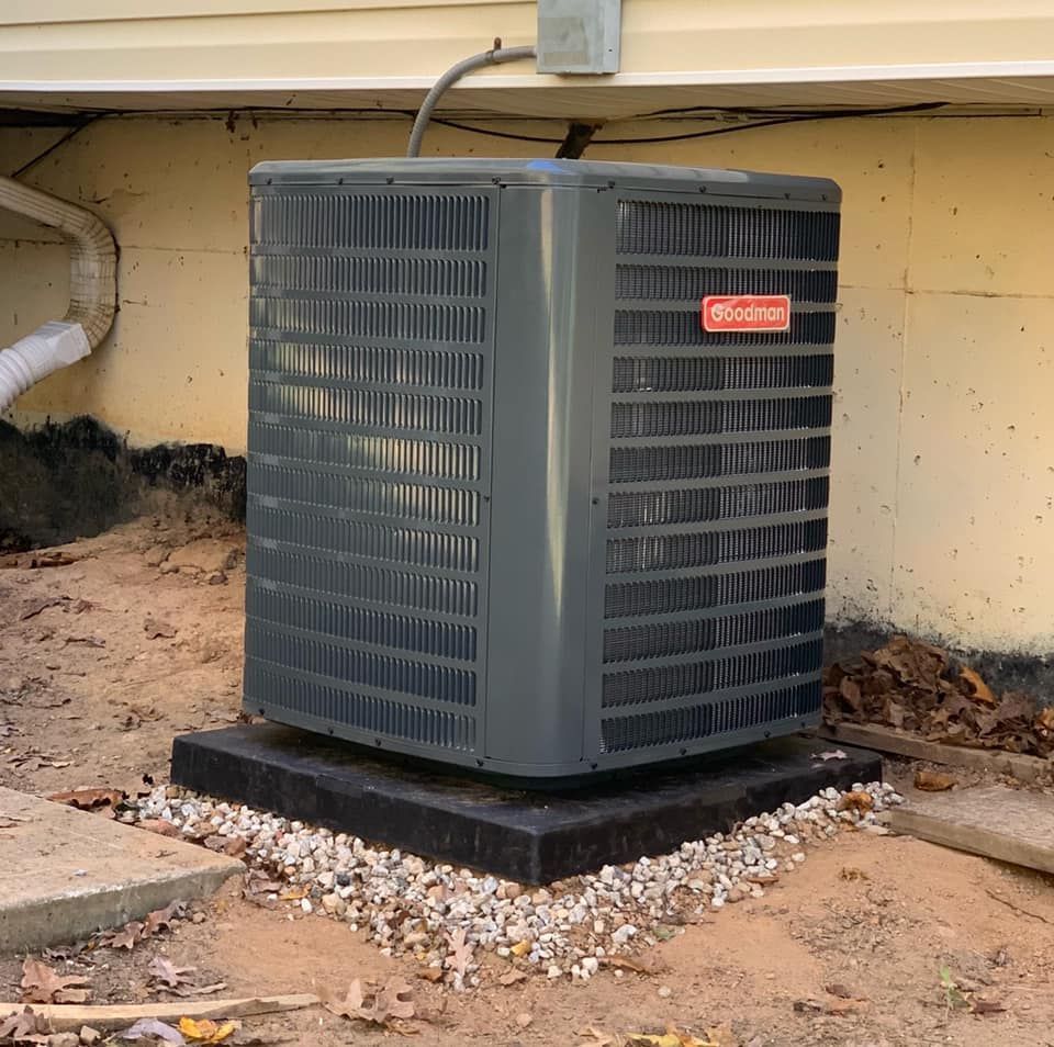 An air conditioner is sitting on top of a pile of gravel.