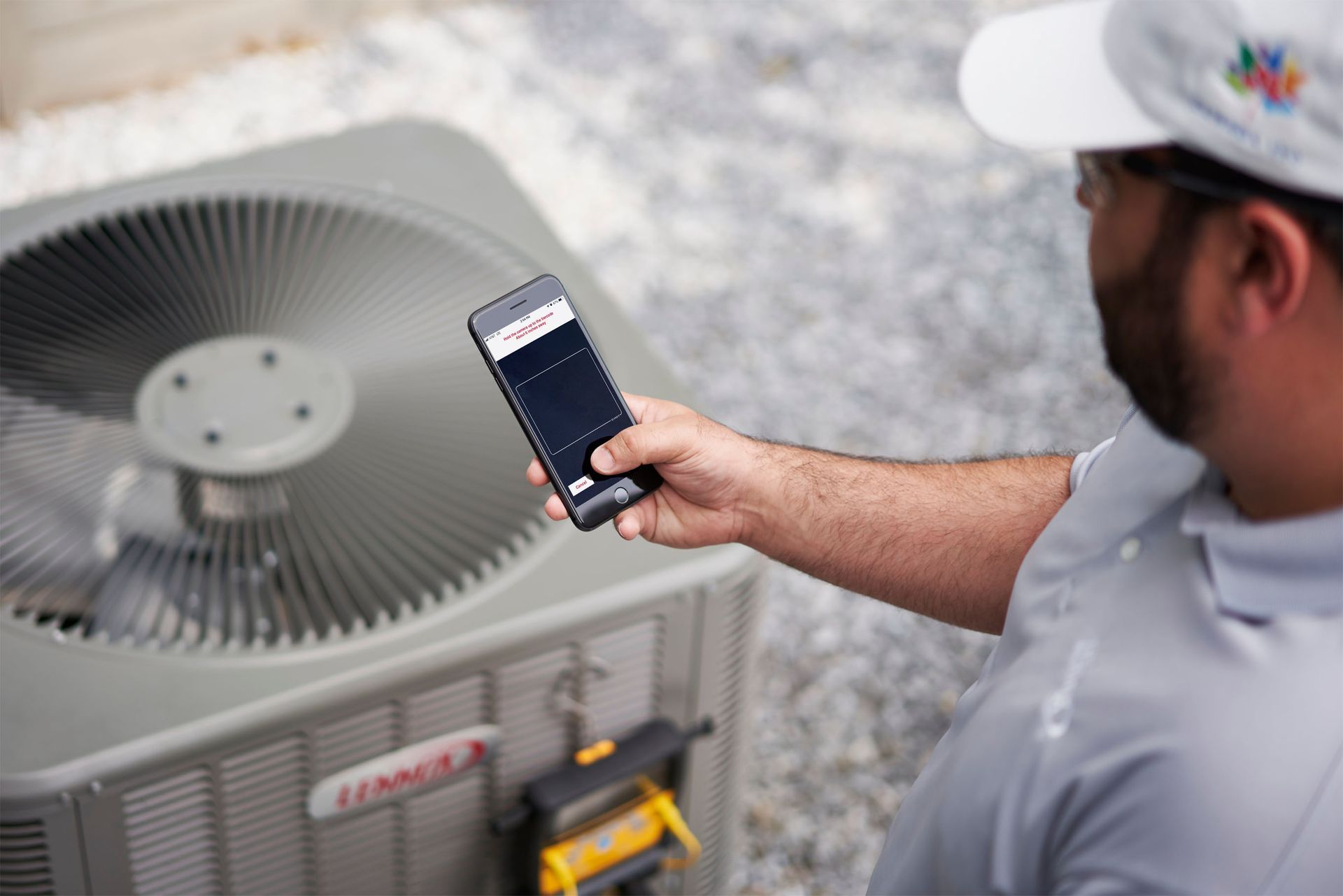 a man is holding a cell phone in front of an air conditioner .
