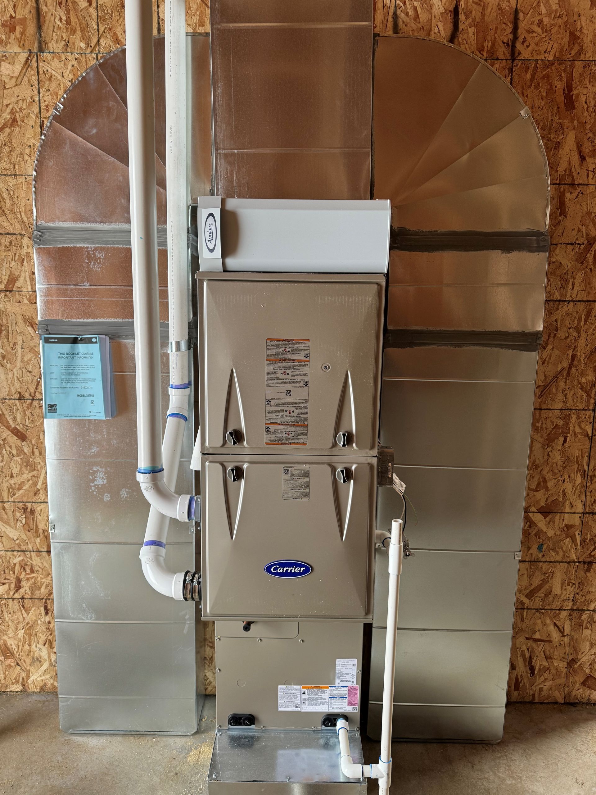 A stainless steel furnace is sitting in a room next to a wall.