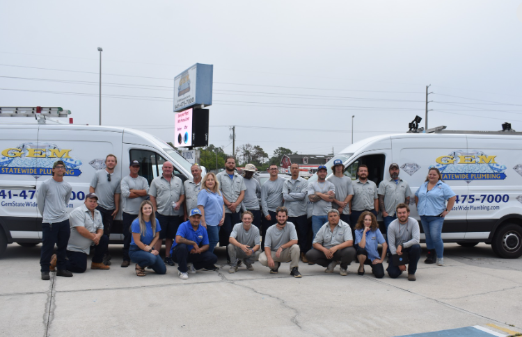 Group photo of a service crew posing between two white vans in a parking lot