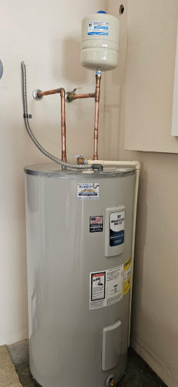 Residential water heater with expansion tank and copper pipes in a utility closet.