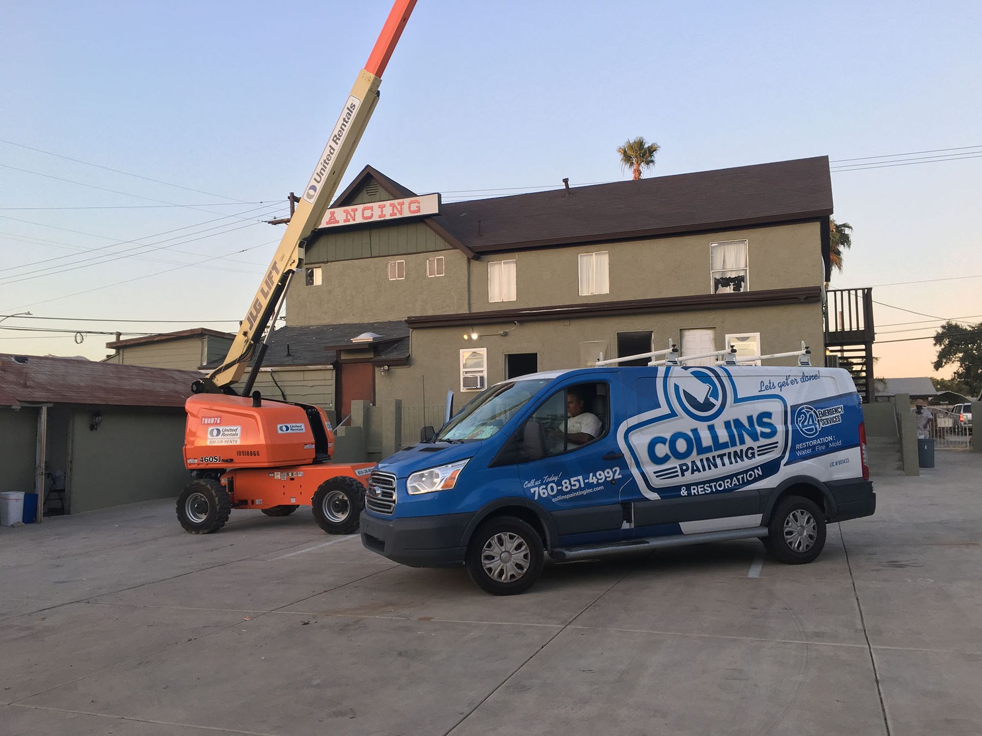 A blue and white van is parked in front of a building.