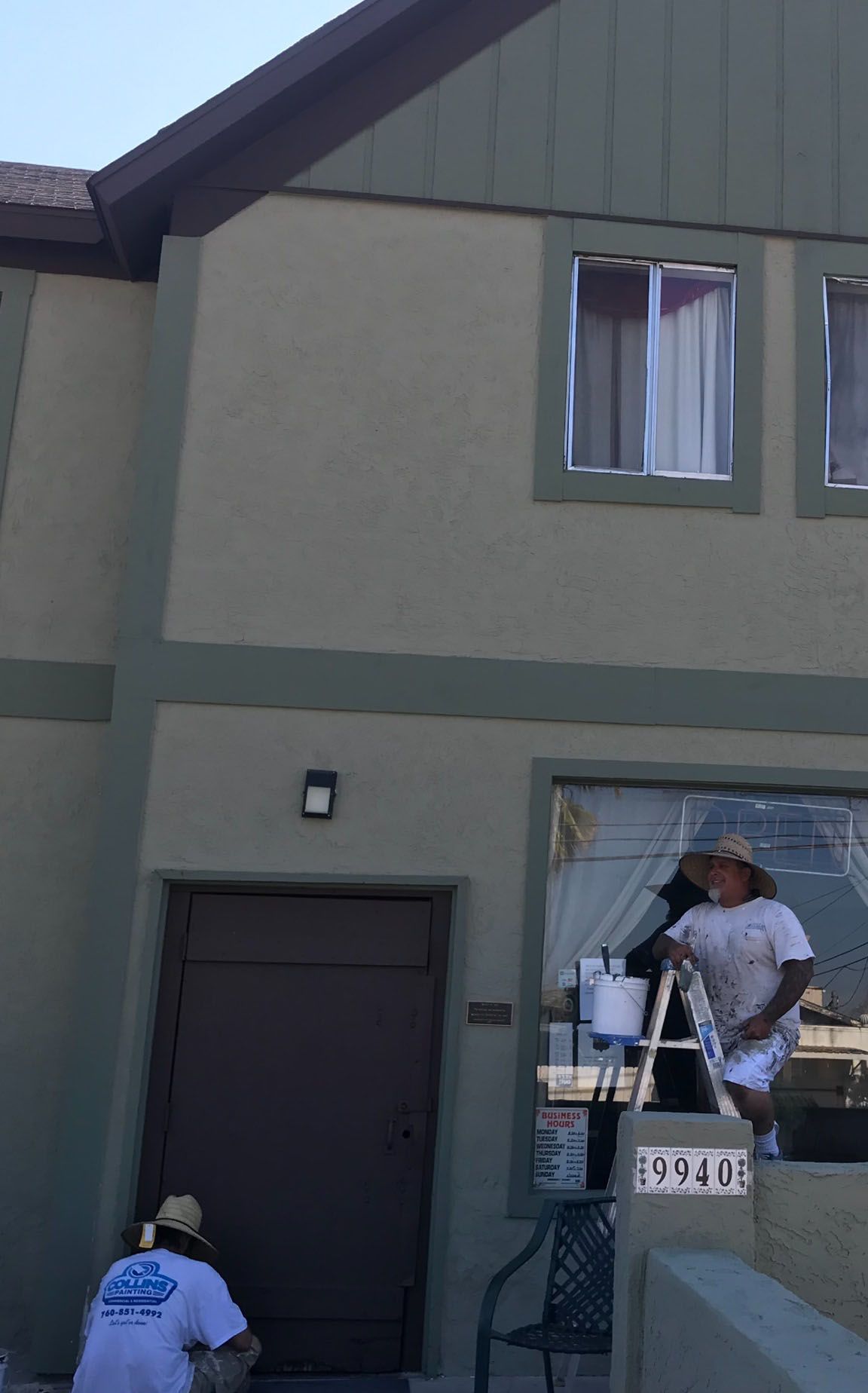 A man is painting the outside of a house with a ladder