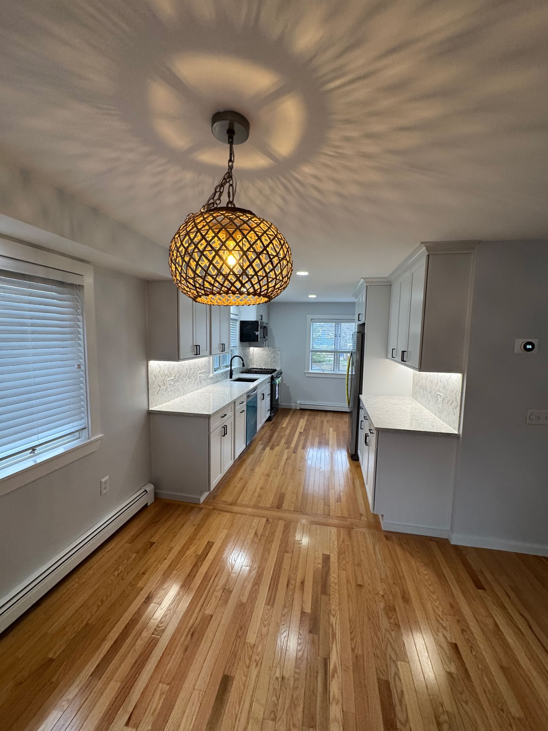 A kitchen with hardwood floors and a pendant light hanging from the ceiling.