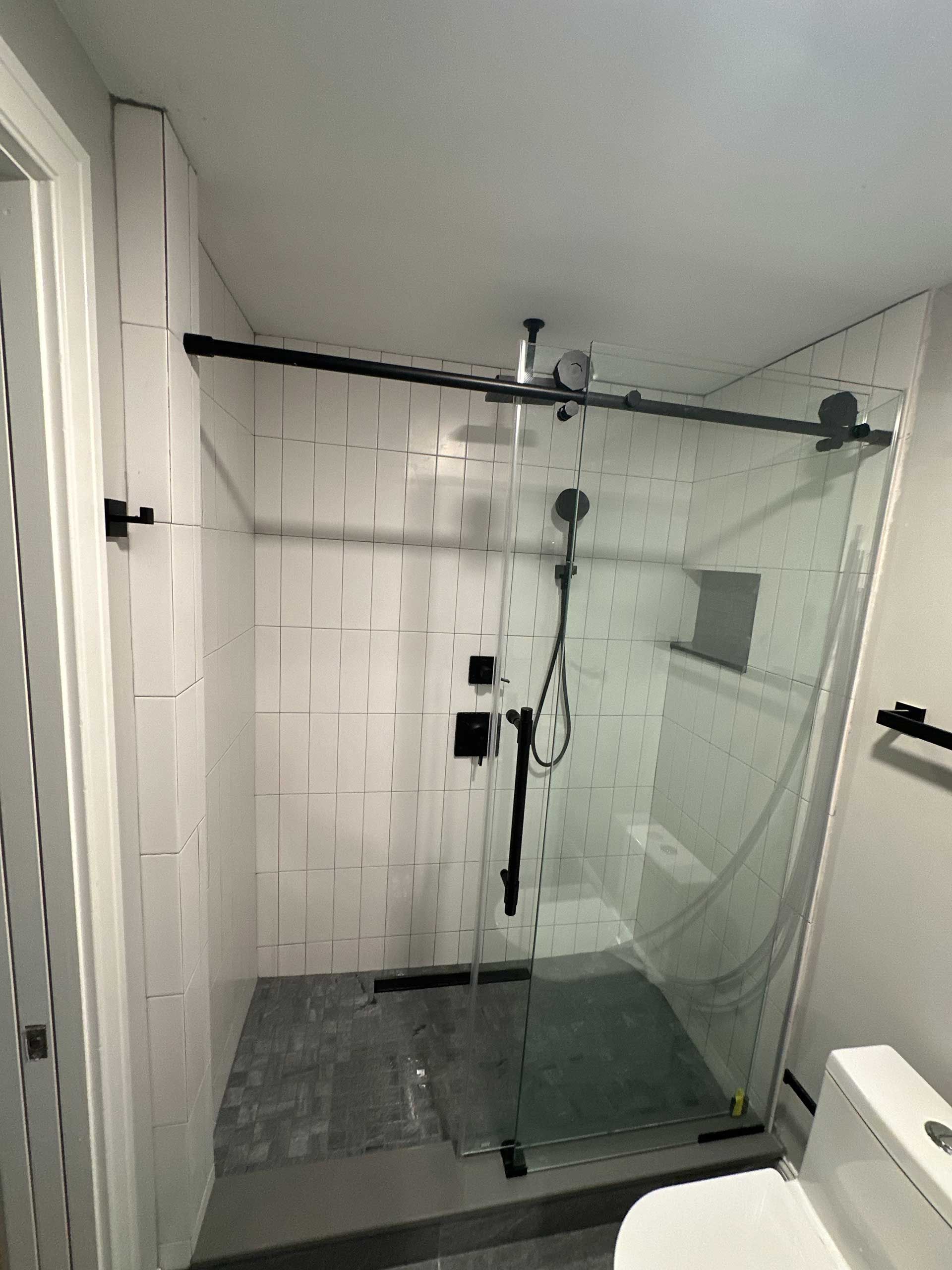 a bathroom with a sliding glass shower door and a toilet