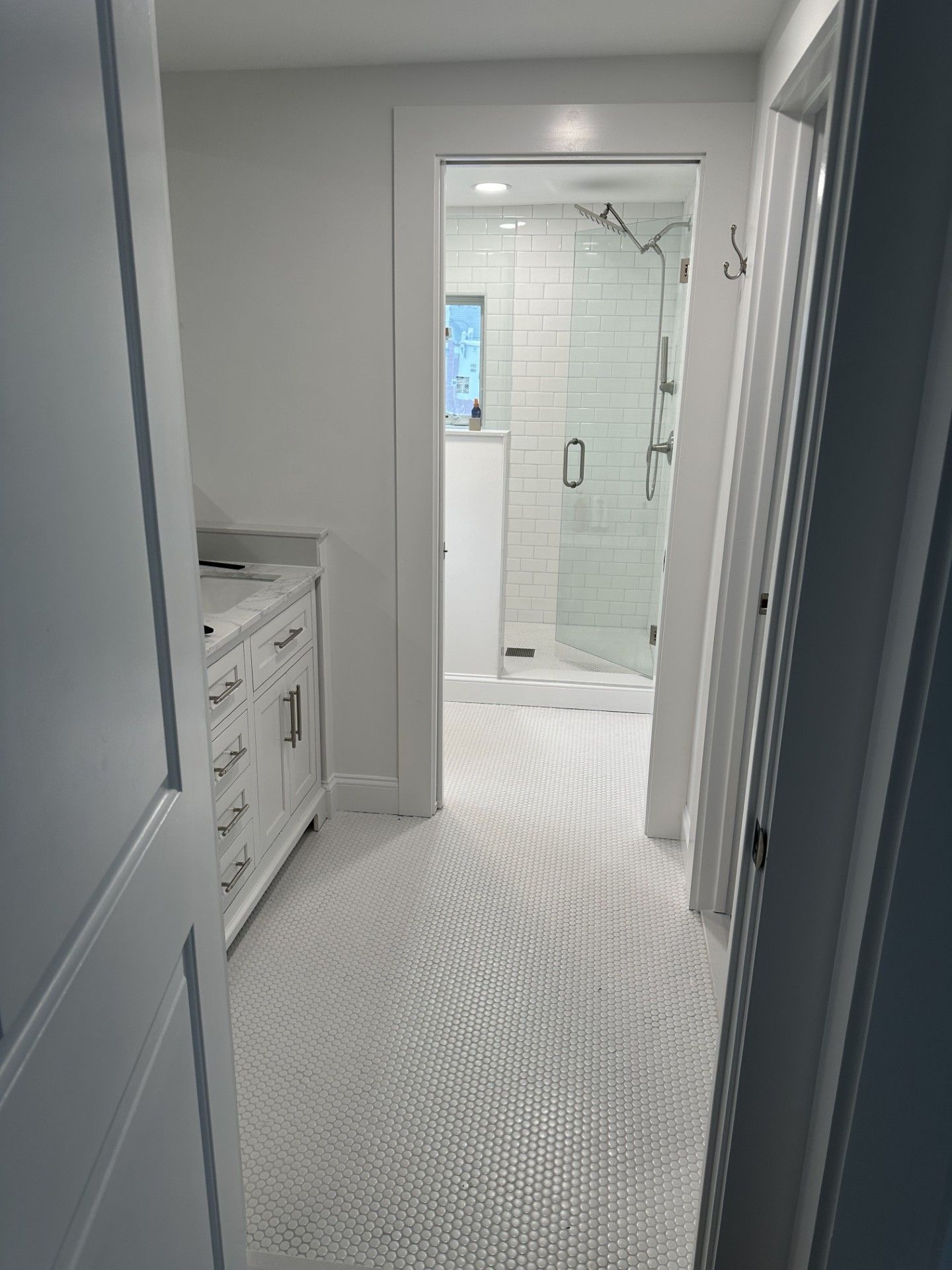 A hallway leading to a bathroom with a walk-in shower