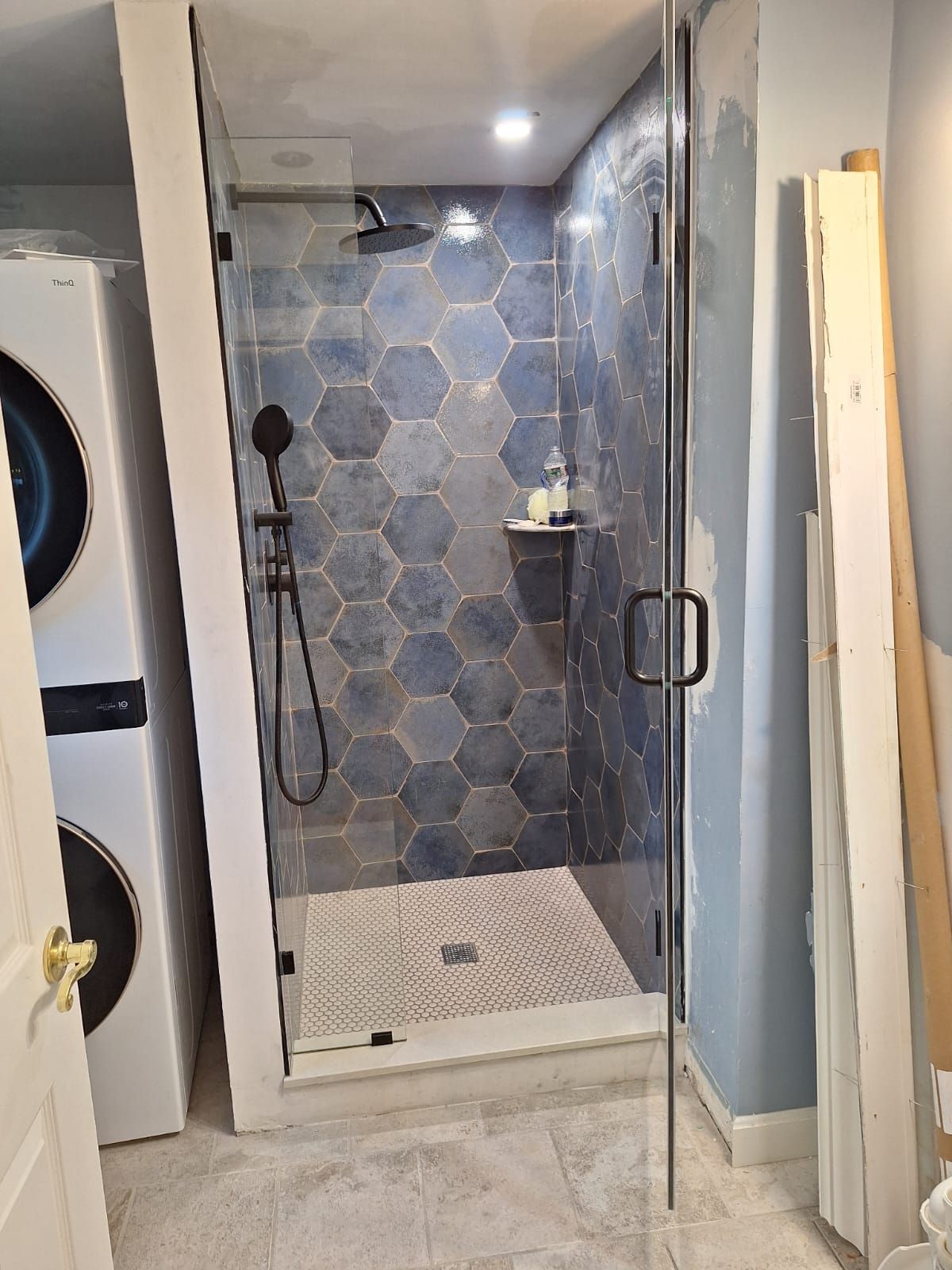 A bathroom with a walk-in shower and a washer and dryer