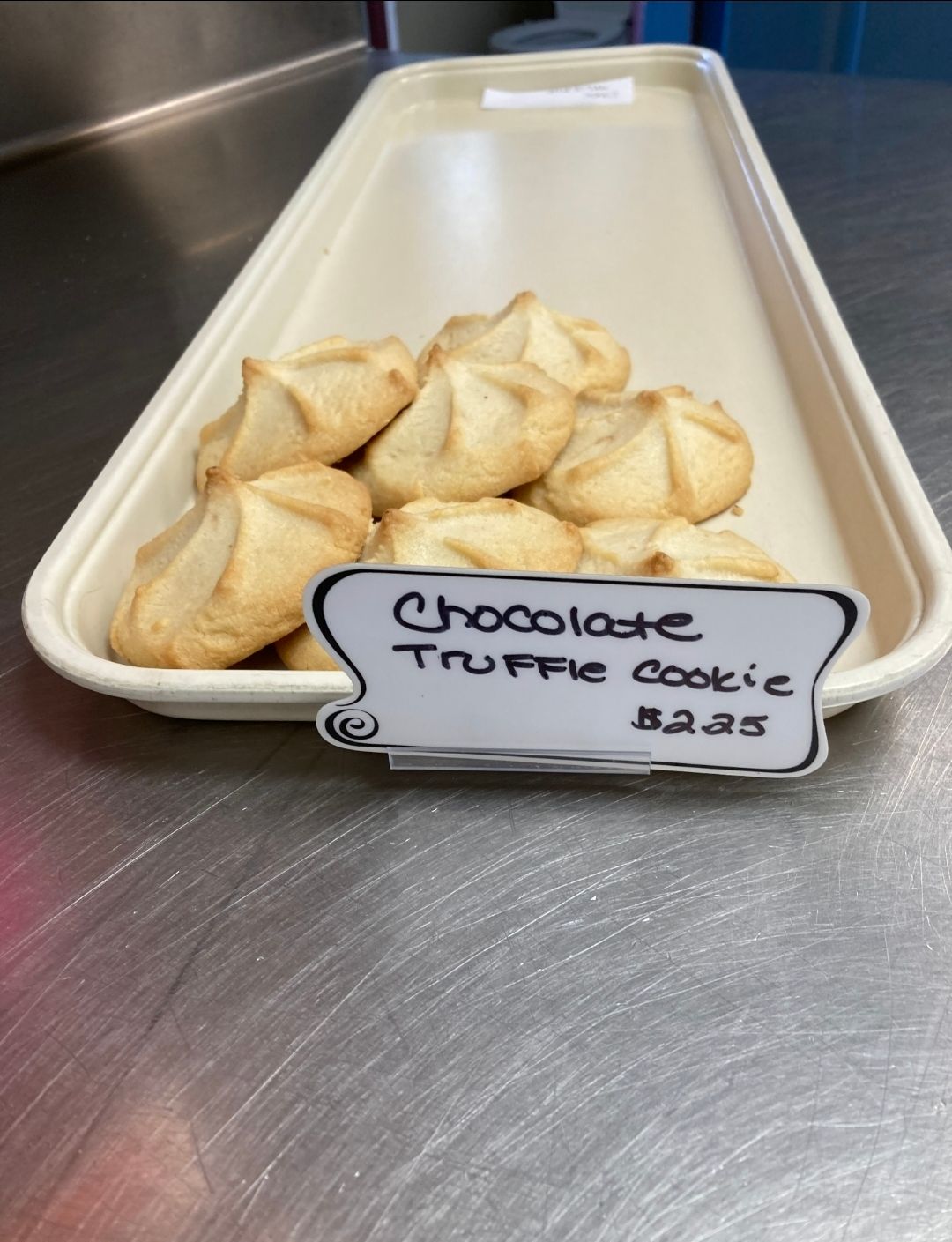 Tray of churro cookies with a handwritten label on a stainless steel counter.