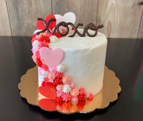 white cake with hearts and the word xoxo on top