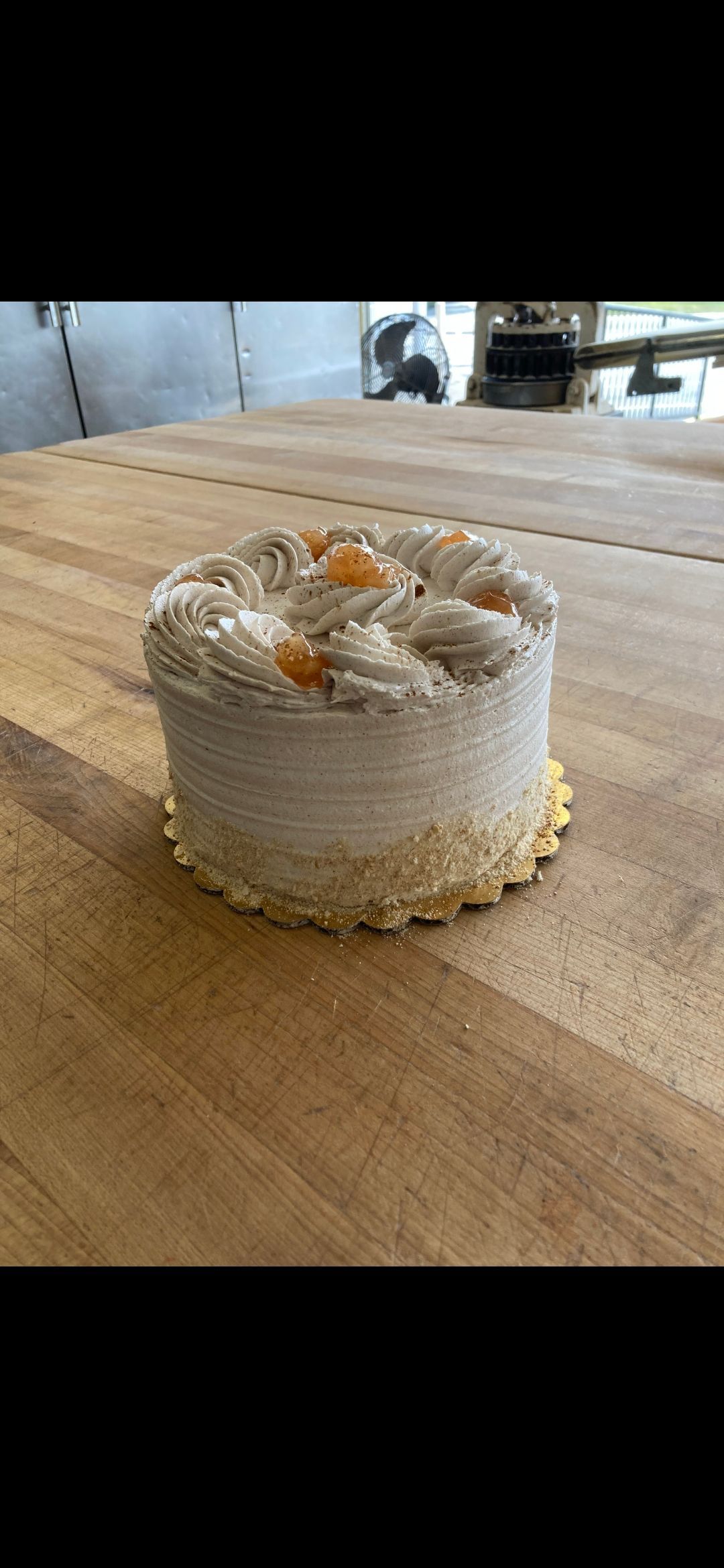 Small frosted cake with caramel drizzle on a wooden table