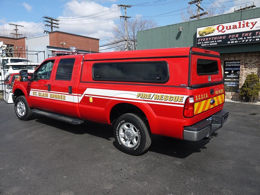 A red St. James Fire Rescue pickup truck with a camper shell parked in an outdoor lot on a sunny day.