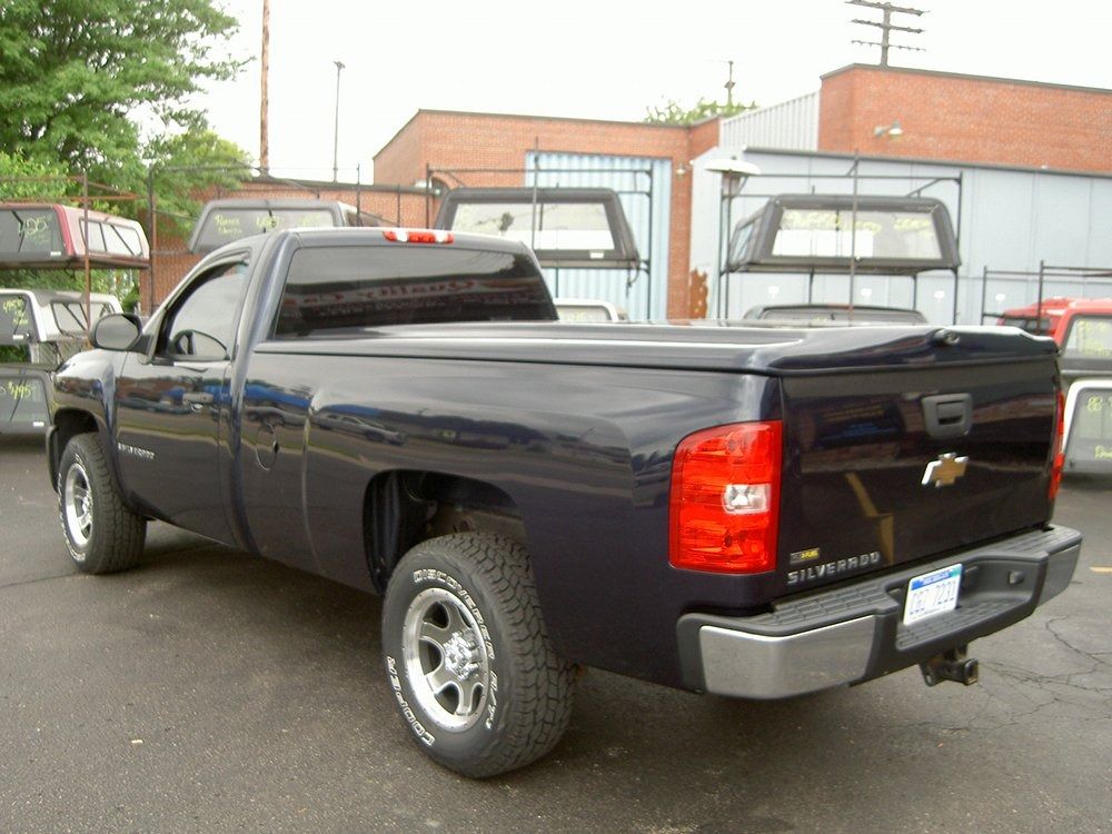 A dark blue Chevrolet Silverado pickup truck with a tonneau bed cover parked in an outdoor lot.