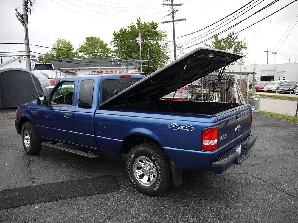 A blue Ford Ranger pickup truck with its tonneau cover open, parked in an outdoor lot.