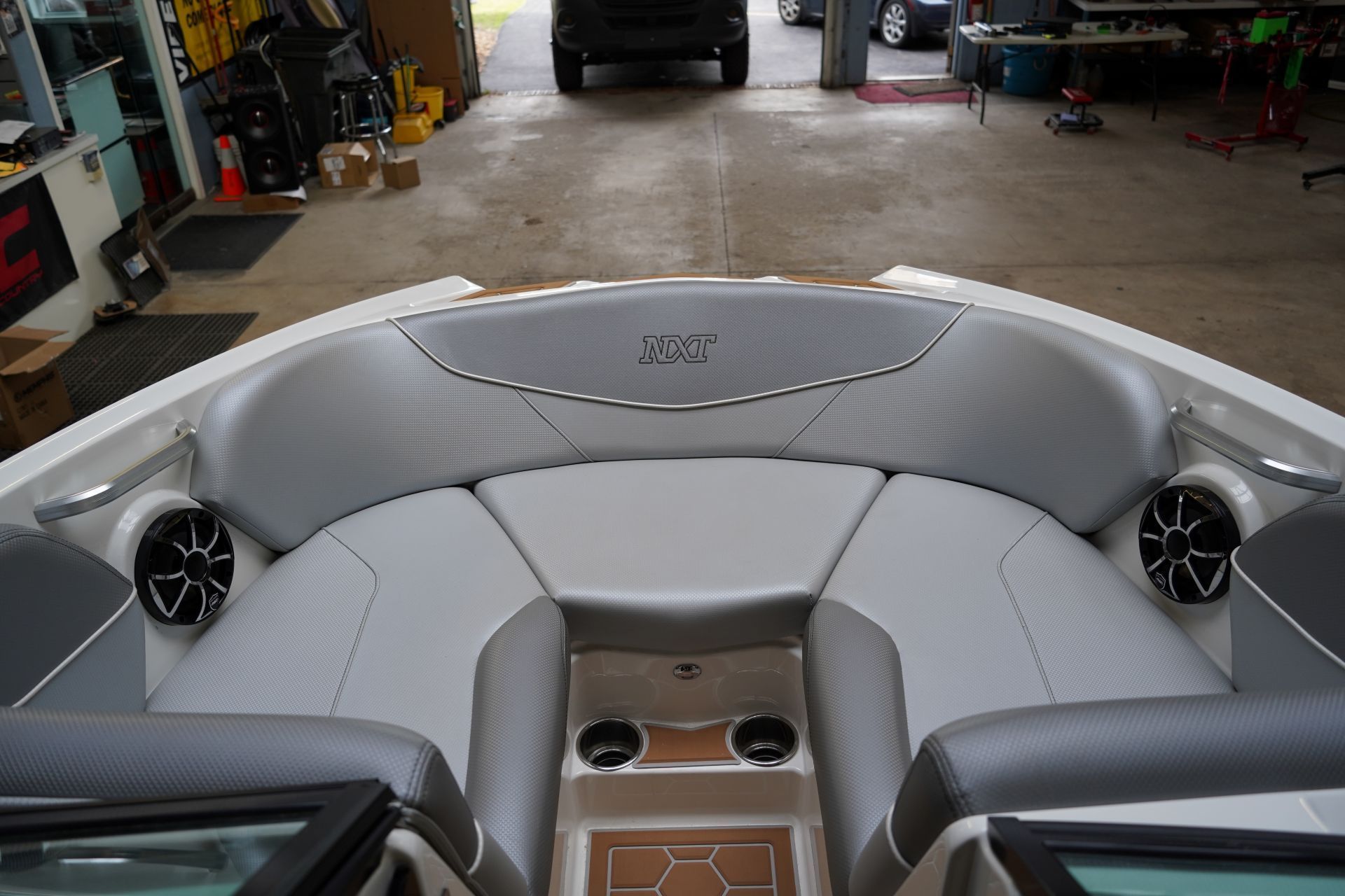 The back of a boat with speakers on it is in a garage.