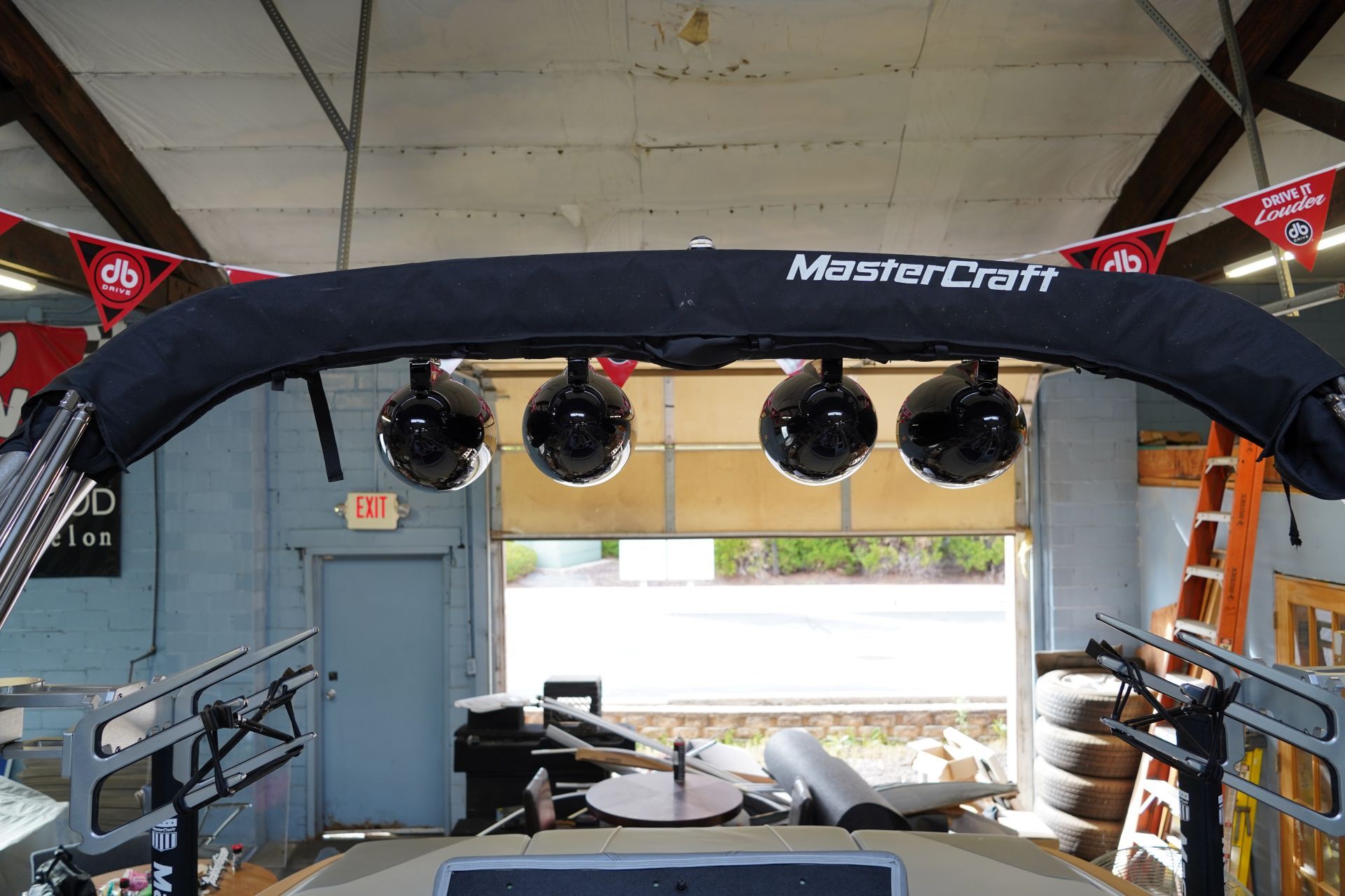 A boat is sitting in a garage with speakers on the top of it.