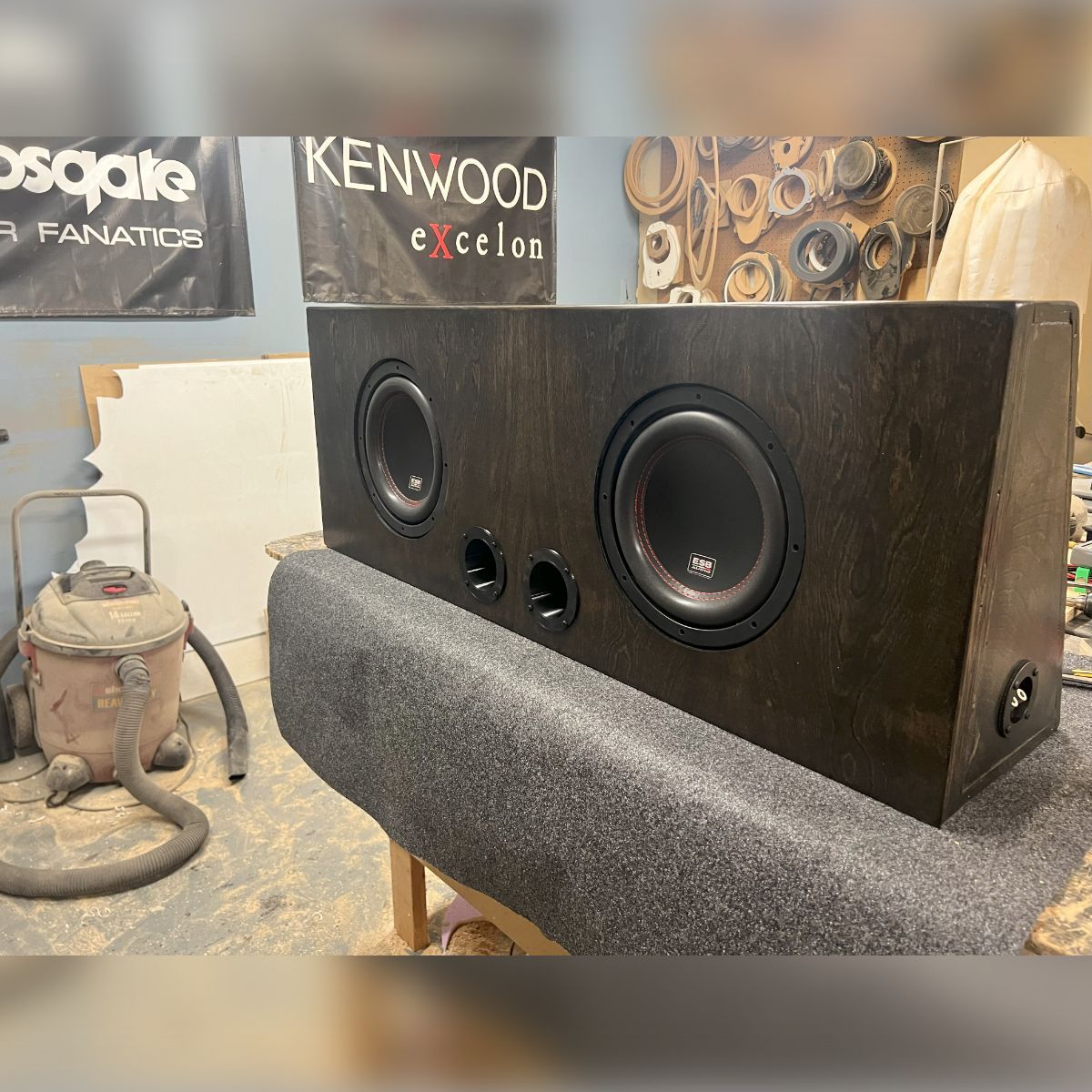 A kenwood speaker is sitting on a table next to a vacuum cleaner