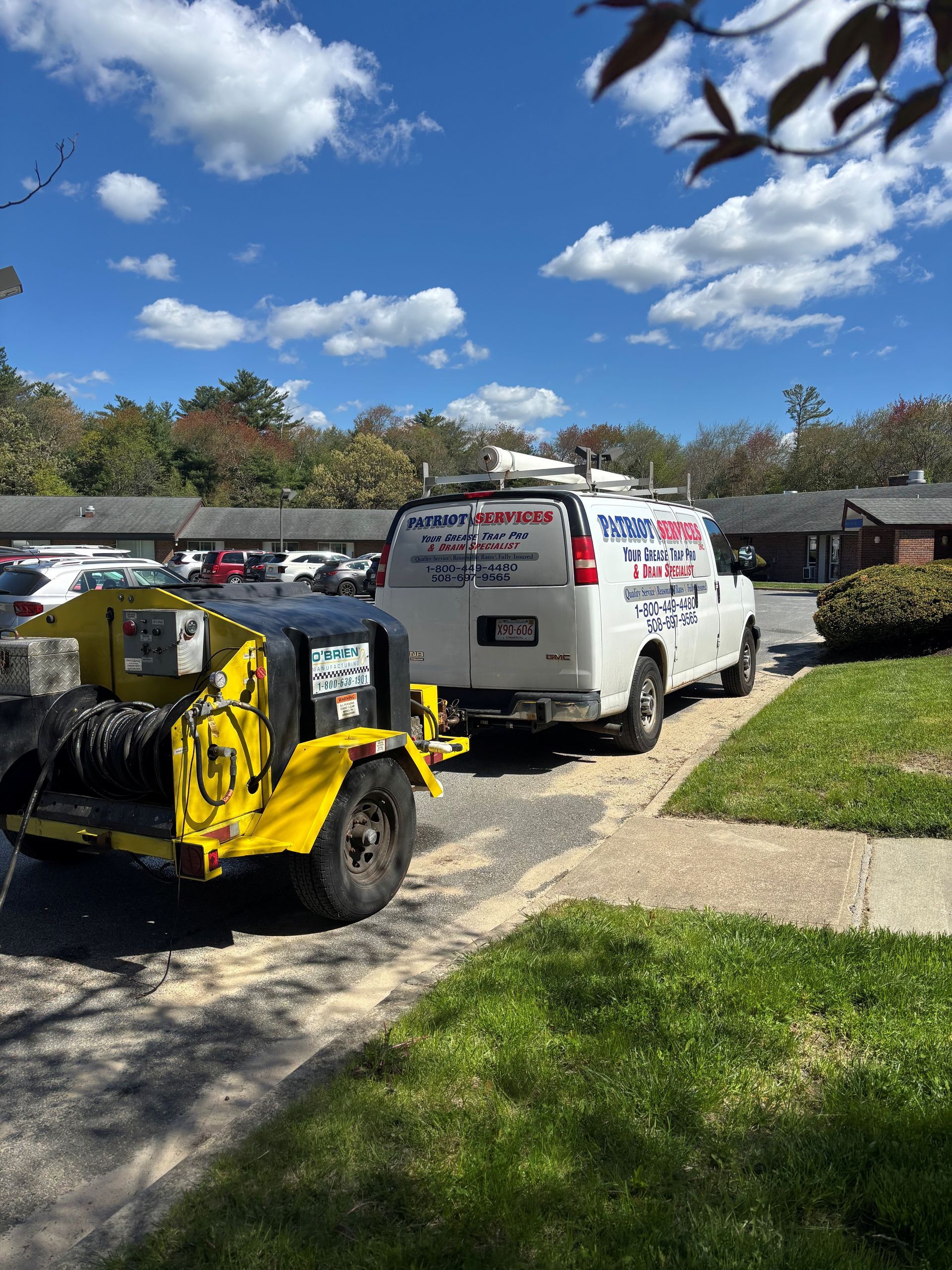 Yellow utility cart and white service van parked on a sunny residential street under a blue sky.