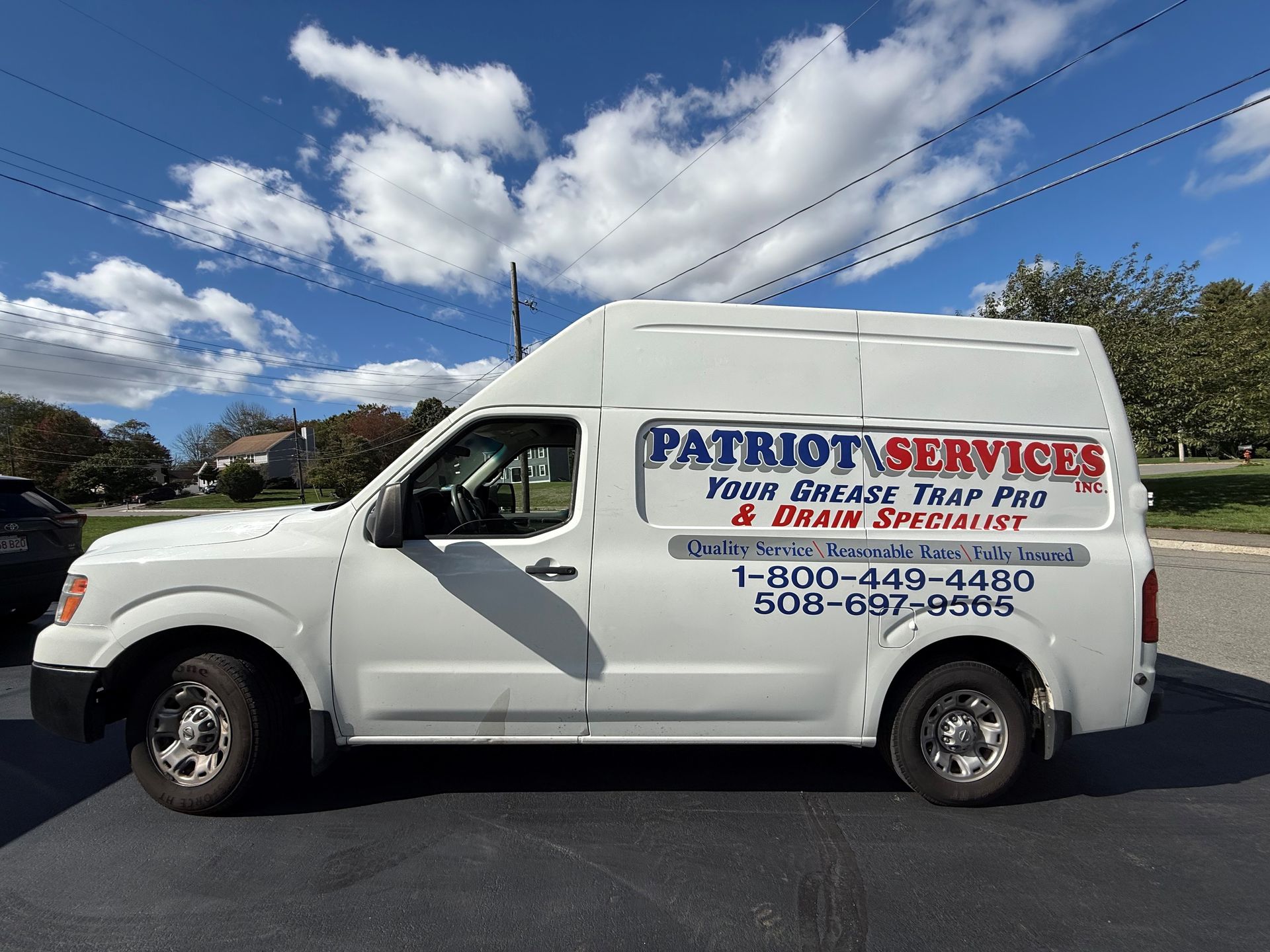 White Patriot Services van parked outdoors with blue sky and clouds.