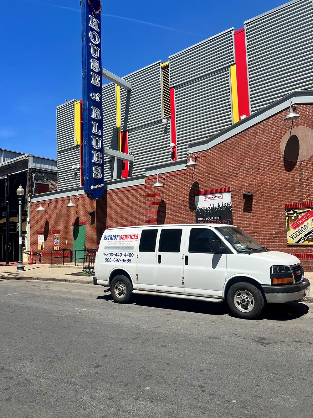 White van parked on street in front of a brick building with a theater sign and colorful accents.