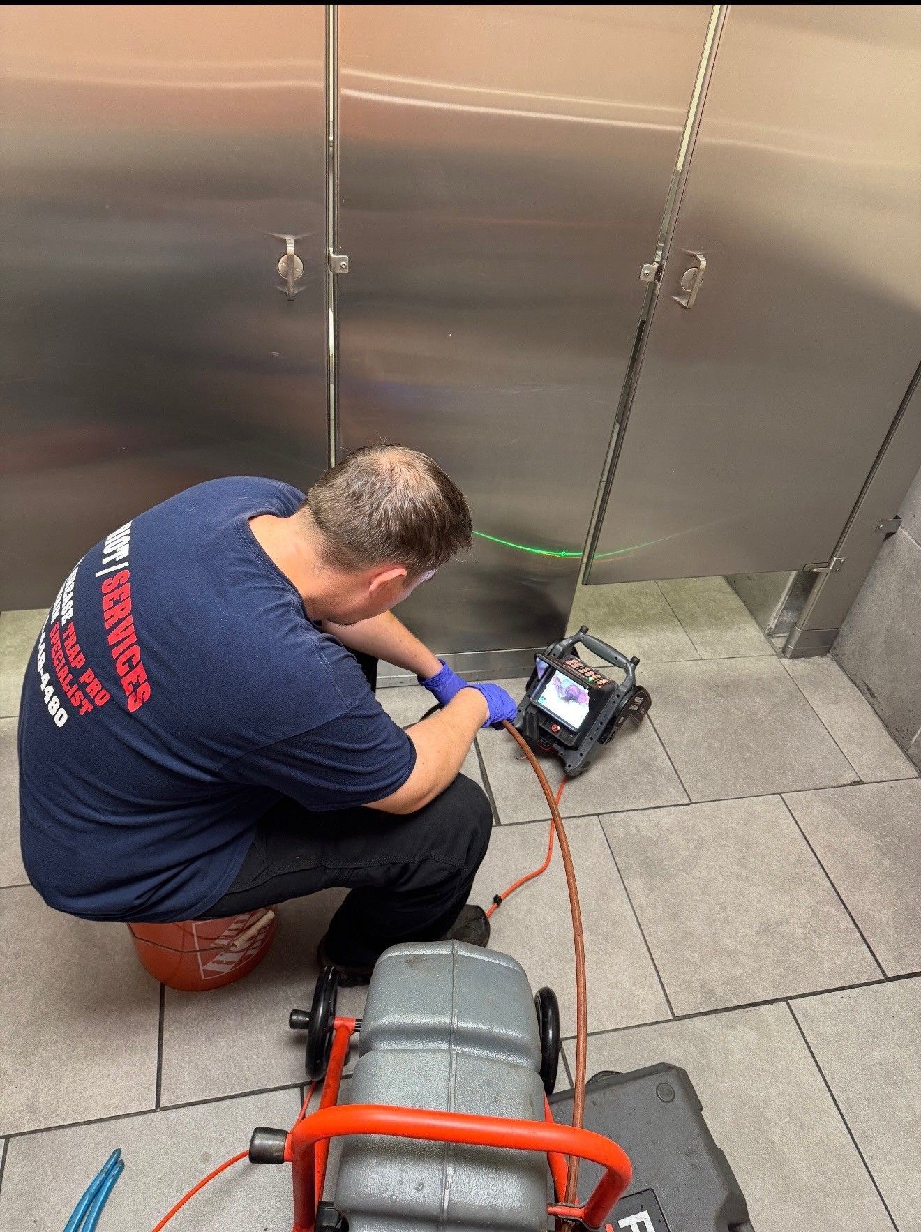 Plumber using a camera to inspect a drain in a public restroom.