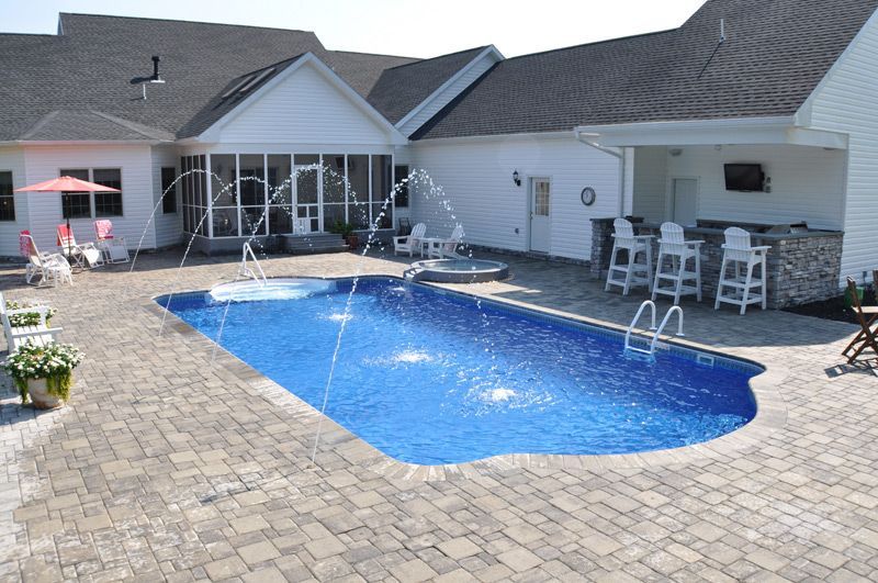 A large swimming pool is in the backyard of a house