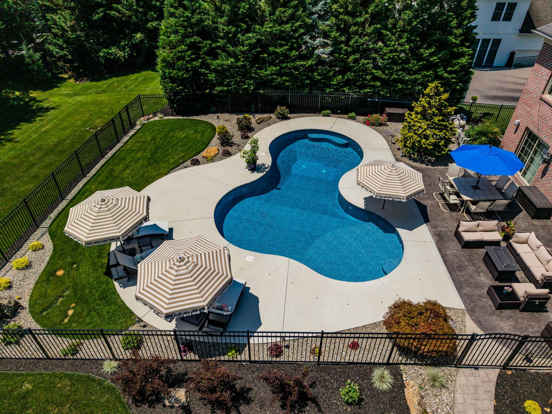 An aerial view of a large swimming pool surrounded by umbrellas and furniture.
