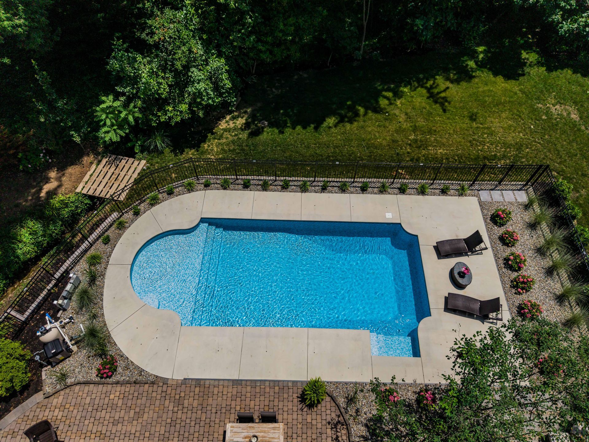 An aerial view of a large swimming pool in a backyard surrounded by trees.