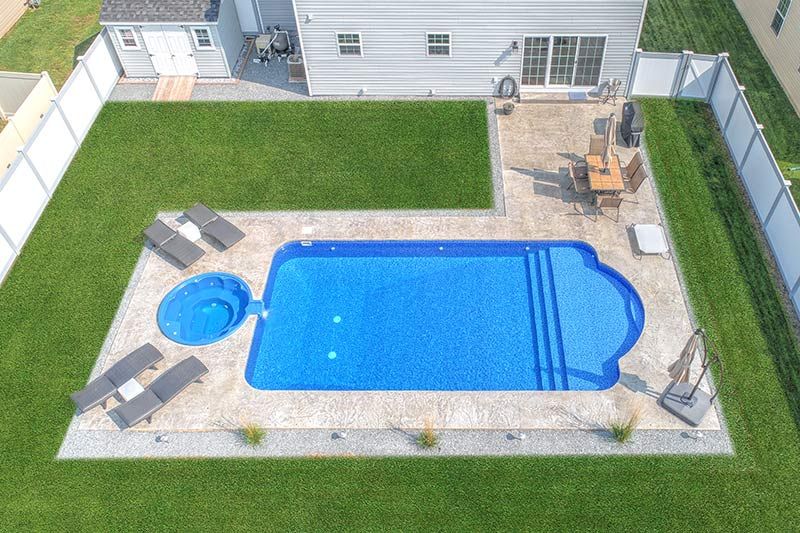 An aerial view of a large swimming pool in the backyard of a house.