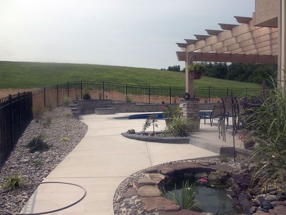 A patio area with a pergola and a pond