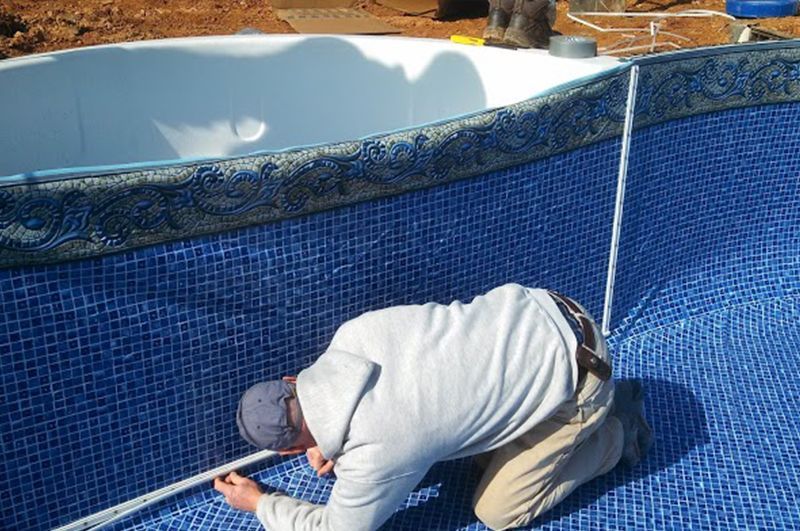 A man is measuring a pool with a tape measure