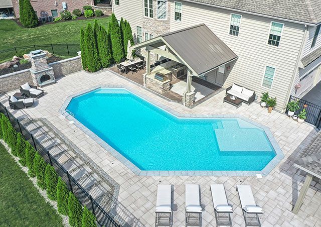 An aerial view of a large swimming pool in front of a house.