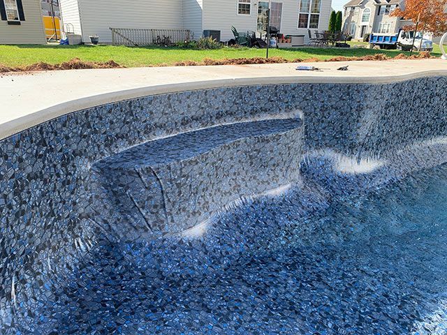 A swimming pool is being built in a backyard with a house in the background.